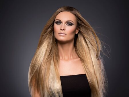Hair beautiful long blond hairstyle woman fashion makeup healthy skin and hair black background. Studio shot.の写真素材