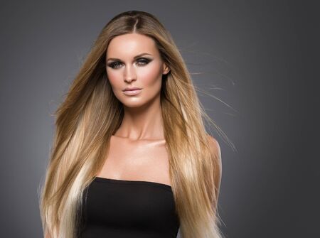 Hair beautiful long blond hairstyle woman fashion makeup healthy skin and hair black background. Studio shot.の写真素材