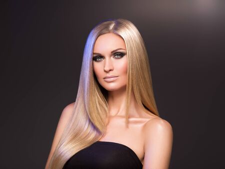 Hair beautiful long blond hairstyle woman fashion makeup healthy skin and hair black background. Studio shot.の写真素材