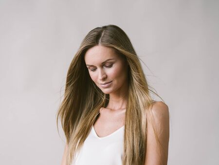 Beautiful woman natural portrait girl with long blonde hair over white gray wall. Studio shot.の写真素材