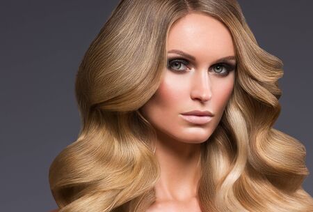 Blond woman long hair curly natural fashion makeup. Studio shot.の写真素材