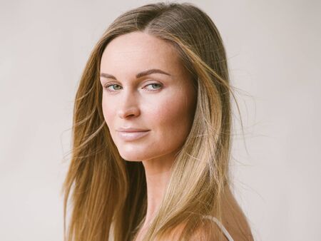 Beautiful woman natural portrait girl with long blonde hair over white gray wall. Studio shot.の写真素材