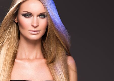 Hair beautiful long blond hairstyle woman fashion makeup healthy skin and hair black background. Studio shot.の写真素材