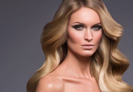Blond woman long hair curly natural fashion makeup. Studio shot.の写真素材