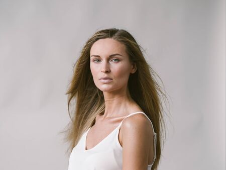 Beautiful woman natural portrait girl with long blonde hair over white gray wall. Studio shot.の写真素材