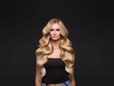 Blond woman long hair curly natural fashion makeup. Studio shot.の写真素材