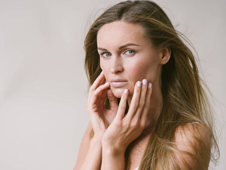 Beautiful woman natural portrait girl with long blonde hair over white gray wall. Studio shot.の写真素材