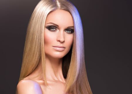 Hair beautiful long blond hairstyle woman fashion makeup healthy skin and hair black background. Studio shot.の写真素材