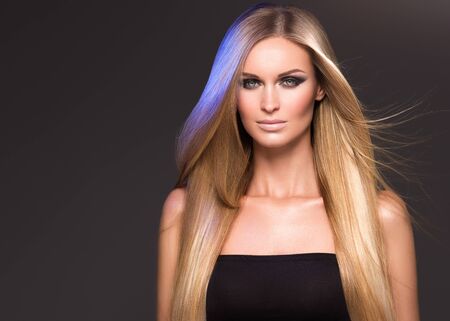 Hair beautiful long blond hairstyle woman fashion makeup healthy skin and hair black background. Studio shot.の写真素材