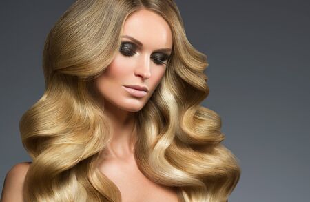 Blond woman long hair curly natural fashion makeup. Studio shot.の写真素材