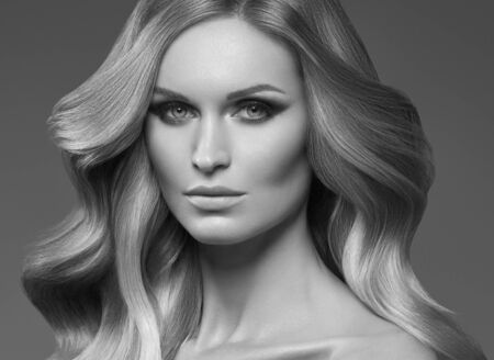 Healthy curly hair woman long blonde hairstyle female. Studio shot. Monochrome. Gray. Black and white.の写真素材
