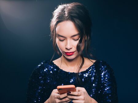 Woman in sequin dress night club concept red lips asian beauty. Studio shot.の写真素材