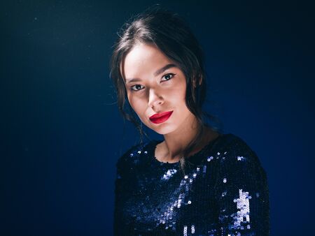 Woman in sequin dress night club concept red lips asian beauty. Studio shot.の写真素材