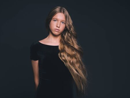 Long hair beauty girl healthy curly long hairstyle blonde in black dress. Studio shot.の写真素材