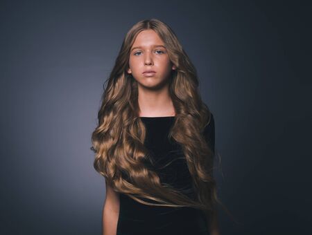 Long hair beauty girl healthy curly long hairstyle blonde in black dress. Studio shot.の写真素材