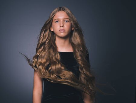 Long hair beauty girl healthy curly long hairstyle blonde in black dress. Studio shot.の写真素材