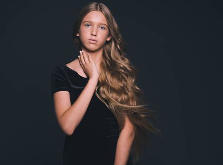 Long hair beauty girl healthy curly long hairstyle blonde in black dress. Studio shot.の写真素材