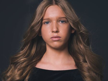 Long hair beauty girl healthy curly long hairstyle blonde in black dress. Studio shot.の写真素材