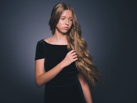 Long hair beauty girl healthy curly long hairstyle blonde in black dress. Studio shot.の写真素材