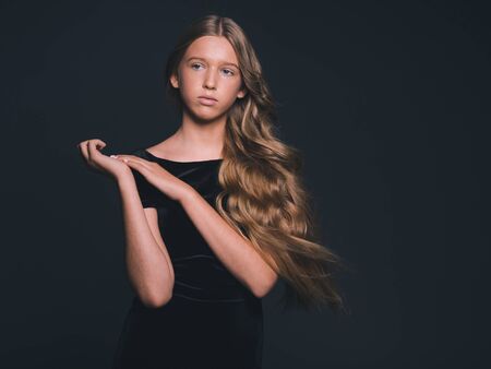 Long hair beauty girl healthy curly long hairstyle blonde in black dress. Studio shot.の写真素材