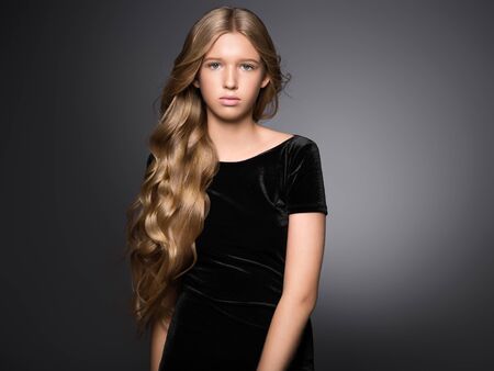 Long hair beauty girl healthy curly long hairstyle blonde in black dress. Studio shot.の写真素材