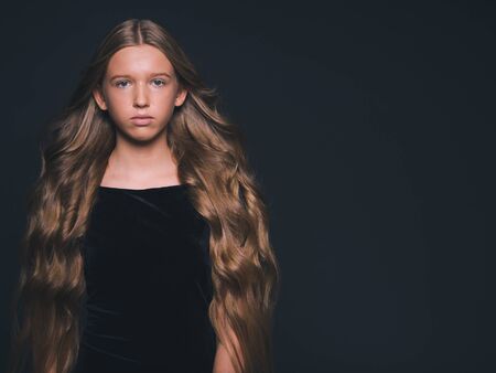 Long hair beauty girl healthy curly long hairstyle blonde in black dress. Studio shot.の写真素材