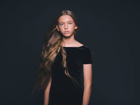 Long hair beauty girl healthy curly long hairstyle blonde in black dress. Studio shot.の写真素材