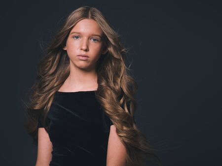 Long hair beauty girl healthy curly long hairstyle blonde in black dress. Studio shot.の写真素材