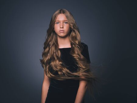 Long hair beauty girl healthy curly long hairstyle blonde in black dress. Studio shot.の写真素材