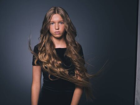 Long hair beauty girl healthy curly long hairstyle blonde in black dress. Studio shot.の写真素材