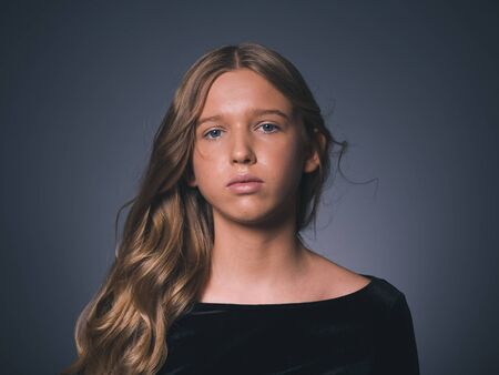 Long hair beauty girl healthy curly long hairstyle blonde in black dress. Studio shot.の写真素材