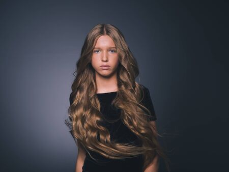 Long hair beauty girl healthy curly long hairstyle blonde in black dress. Studio shot.の写真素材