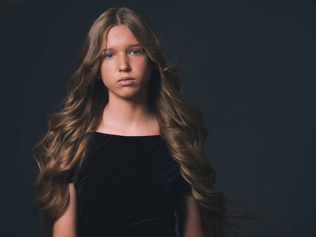 Long hair beauty girl healthy curly long hairstyle blonde in black dress. Studio shot.の写真素材