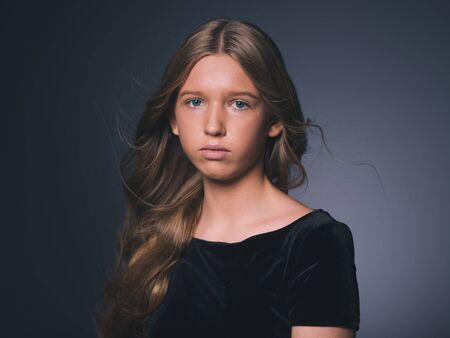 Long hair beauty girl healthy curly long hairstyle blonde in black dress. Studio shot.の写真素材