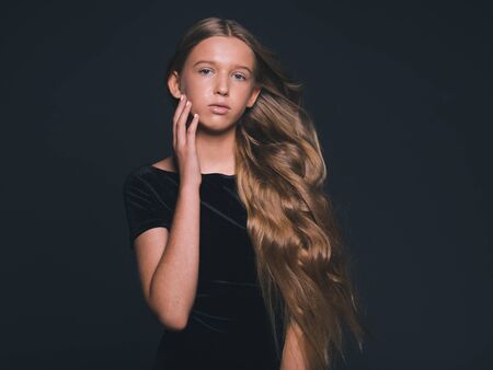 Long hair beauty girl healthy curly long hairstyle blonde in black dress. Studio shot.の写真素材