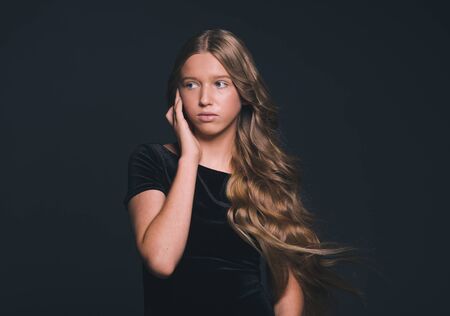 Long hair beauty girl healthy curly long hairstyle blonde in black dress. Studio shot.の写真素材