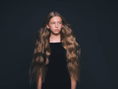 Long hair beauty girl healthy curly long hairstyle blonde in black dress. Studio shot.の写真素材