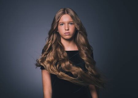 Long hair beauty girl healthy curly long hairstyle blonde in black dress. Studio shot.の写真素材