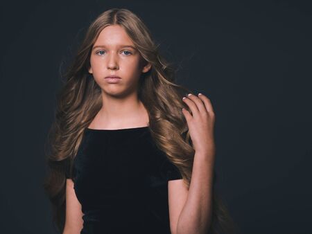 Long hair beauty girl healthy curly long hairstyle blonde in black dress. Studio shot.の写真素材