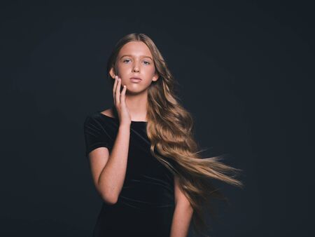 Long hair beauty girl healthy curly long hairstyle blonde in black dress. Studio shot.の写真素材