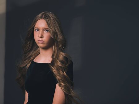 Long hair beauty girl healthy curly long hairstyle blonde in black dress. Studio shot.の写真素材