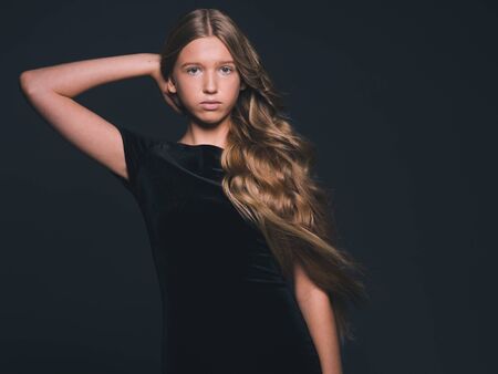 Long hair beauty girl healthy curly long hairstyle blonde in black dress. Studio shot.の写真素材