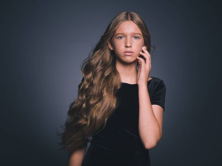 Long hair beauty girl healthy curly long hairstyle blonde in black dress. Studio shot.の写真素材