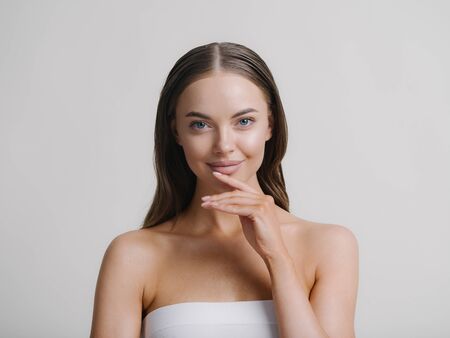 Natural beauty woman with heands touching face long brunette hair beautiful neck and shoulders Studio shot.の写真素材