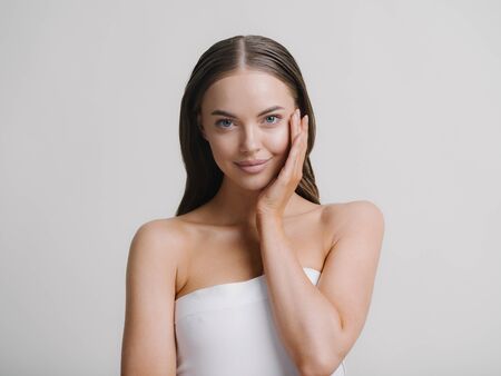 Natural beauty woman with heands touching face long brunette hair beautiful neck and shoulders Studio shot.の写真素材