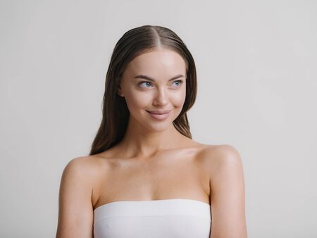 Natural beauty woman with heands touching face long brunette hair beautiful neck and shoulders. Studio shot.の写真素材