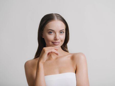 Natural beauty woman with heands touching face long brunette hair beautiful neck and shoulders Studio shot.の写真素材
