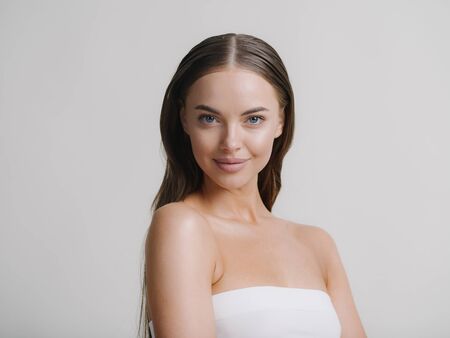 Natural beauty woman with heands touching face long brunette hair beautiful neck and shoulders. Studio shot.の写真素材