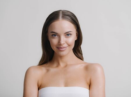 Natural beauty woman with heands touching face long brunette hair beautiful neck and shoulders. Studio shot.の写真素材