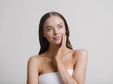 Natural beauty woman with heands touching face long brunette hair beautiful neck and shoulders Studio shot.の写真素材